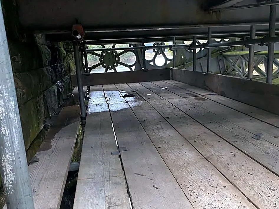 Boarded scaffold platform beneath a bridge deck