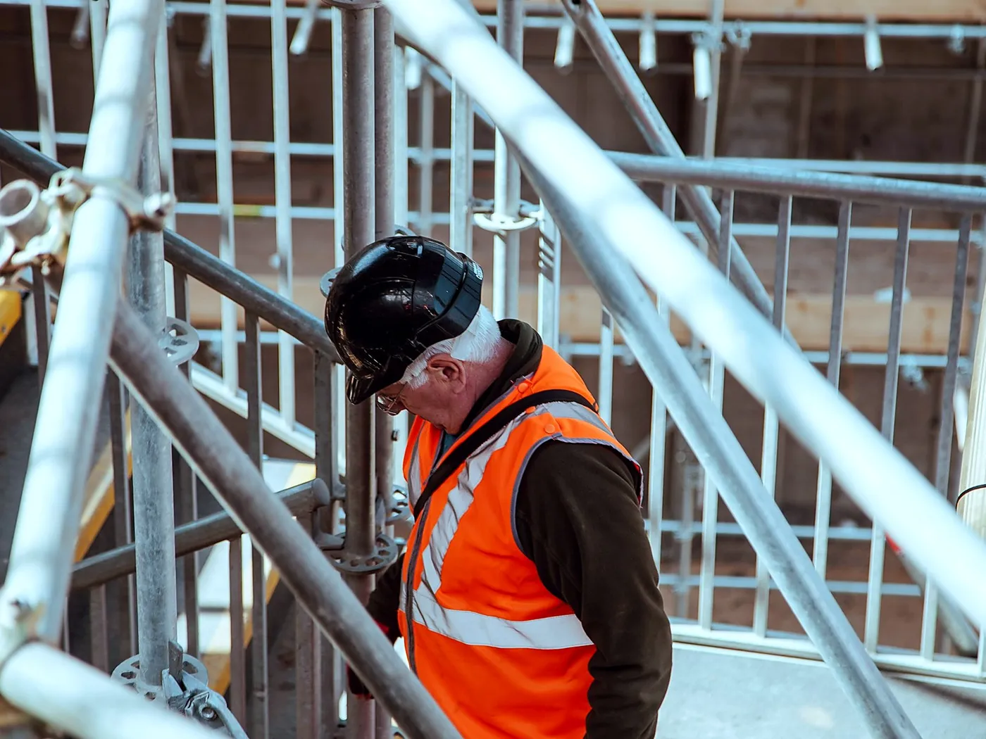 TNT scaffolder in full PPE on a boarded scaffold platform